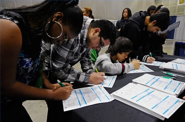 students filling out application form in education fair