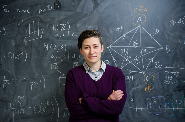Student standing in front of blackboard.